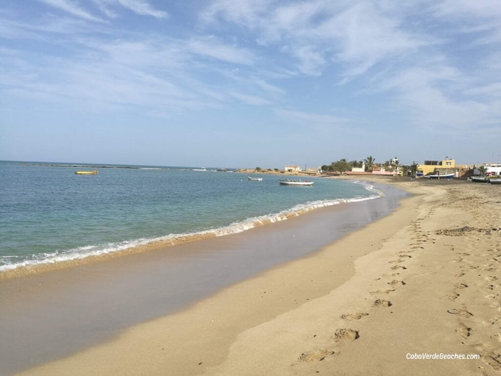 Golden sands and clear waters at Praia de Calheta Beach in Maio, Cape Verde, with fishing boats resting near a tranquil shoreline.