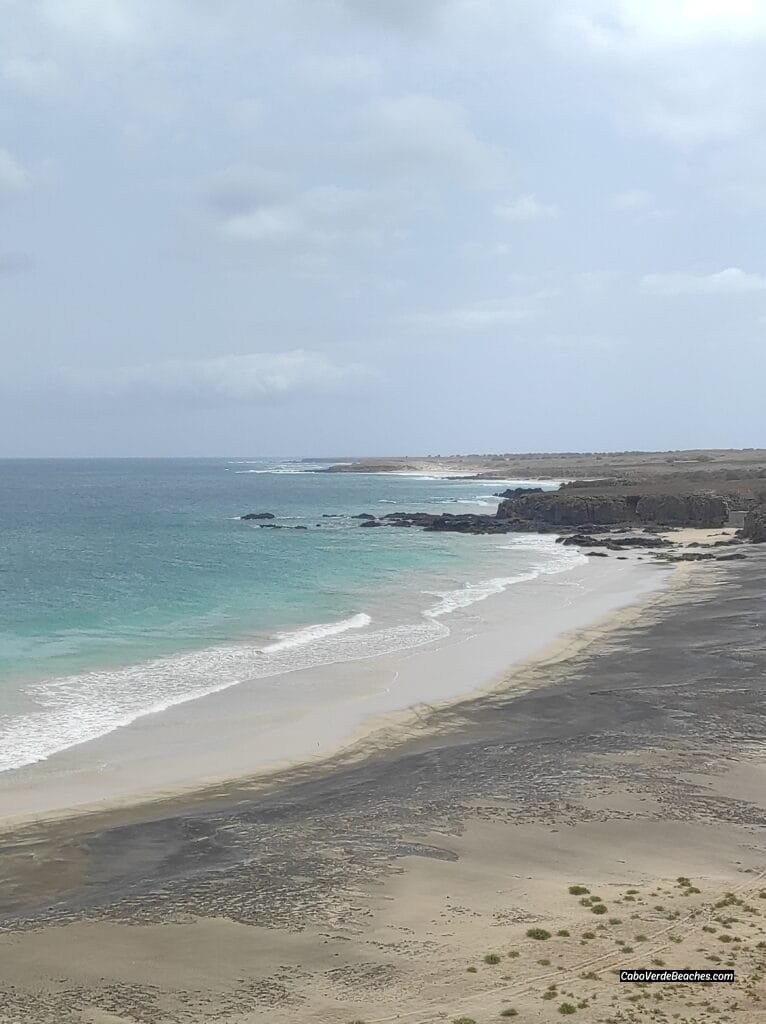 Ribeira Dom João Beach on Maio Island, Cape Verde – sweeping view of white and black sand, clear waters, and untouched natural surroundings under blue sky.