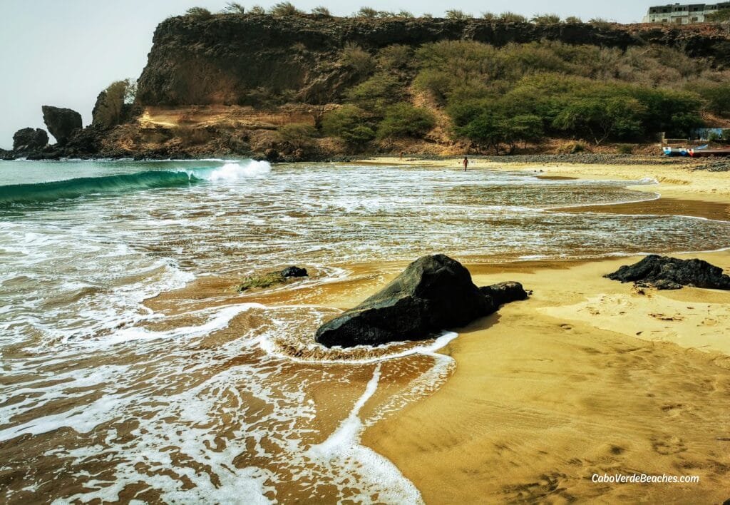Picturesque Portinho Beach on Santiago Island, showcasing its golden sands, turquoise waters, and the surrounding mountainous terrain.