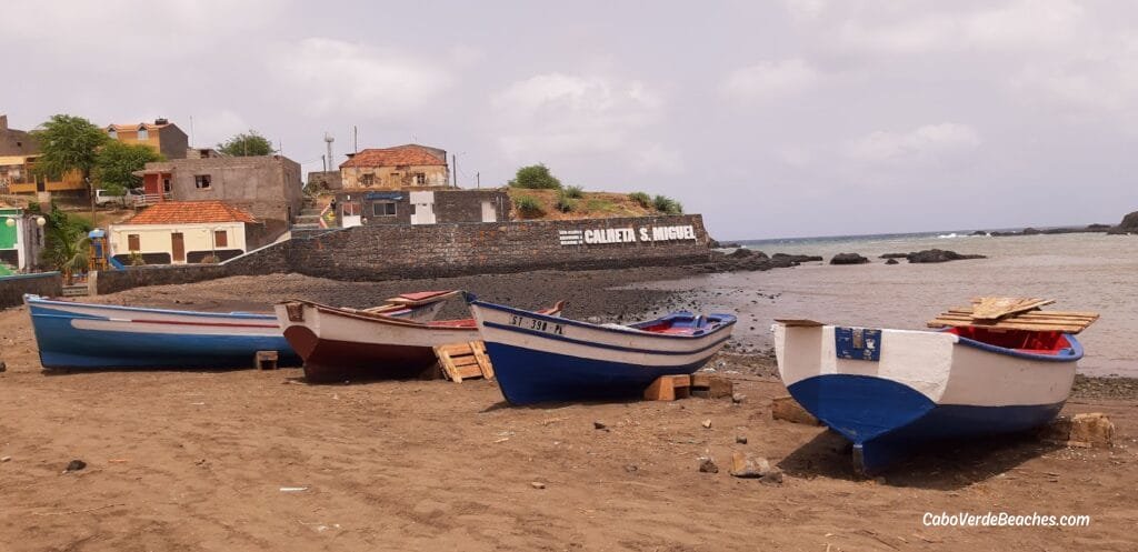 Golden sands and turquoise waters of Porto Calheta Beach, with traditional fishing boats anchored nearby in Santiago, Cape Verde.