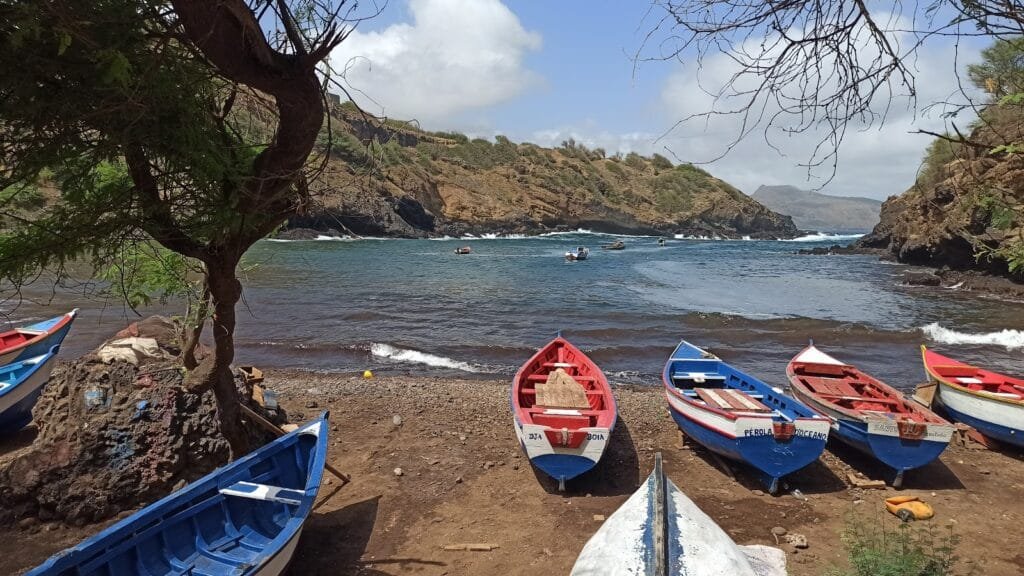 A panoramic view of Porto Formoso Beach, showcasing its pristine sandy cove nestled between rugged cliffs and the turquoise waters of the Atlantic Ocean.​