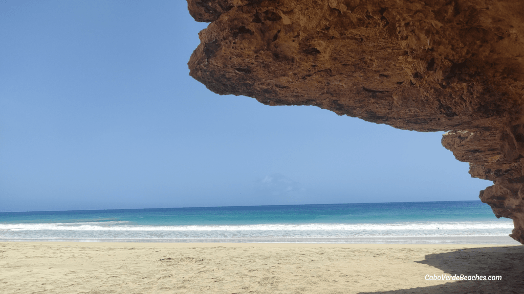 White sandy shore of Ponta Preta Beach with crystal waters and rocky reefs, near Porto Inglês.