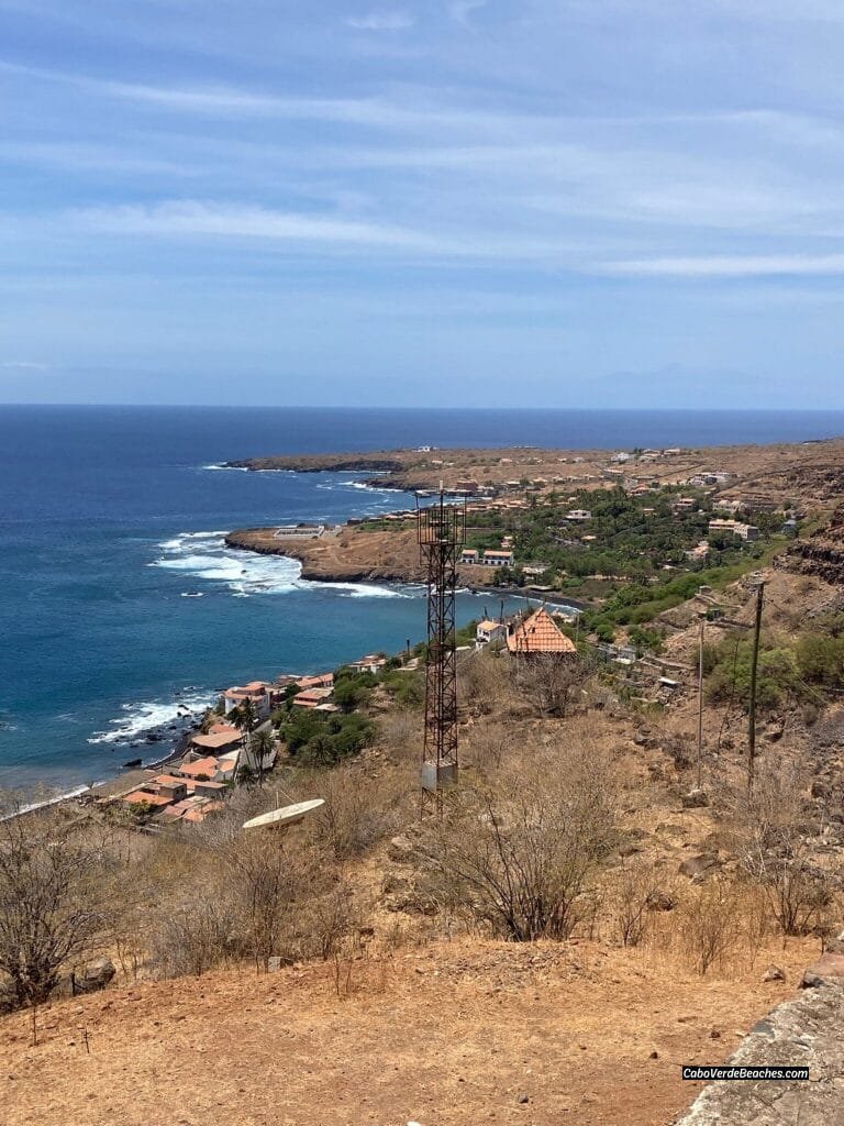 Black sands of Cidade Velha Beach, Cape Verde, meeting the turquoise sea near historic landmarks.