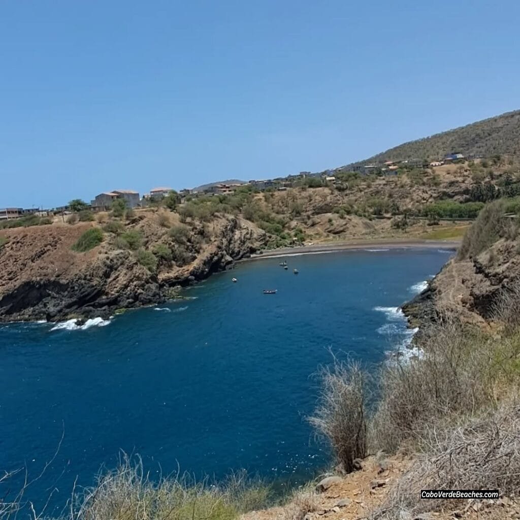 A panoramic view of Porto Formoso Beach, showcasing its pristine sandy cove nestled between rugged cliffs and the turquoise waters of the Atlantic Ocean.​