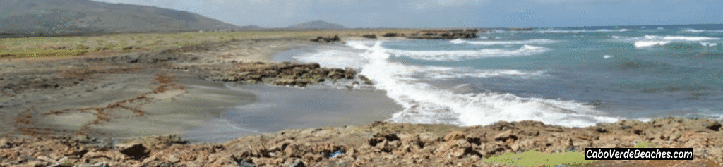 Dramatic cliffs and clear turquoise waters of Ribeira Baía beach in Maio, Cape Verde, under a bright sky.