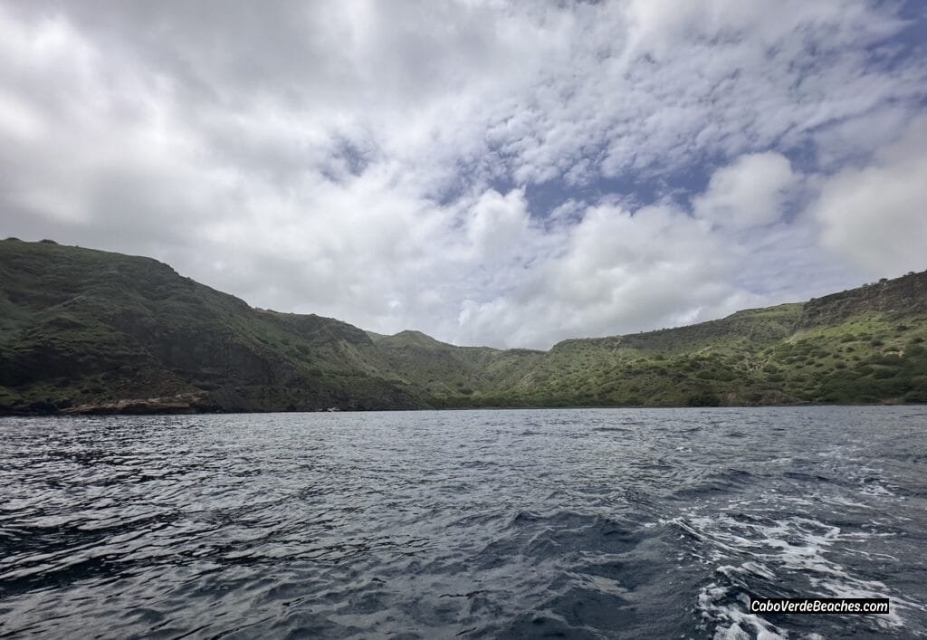 Scenic view of Beach Baia Angra on Santiago Island, Cape Verde, with dark volcanic sand, gentle waves, and lush cliffs surrounding the beach.