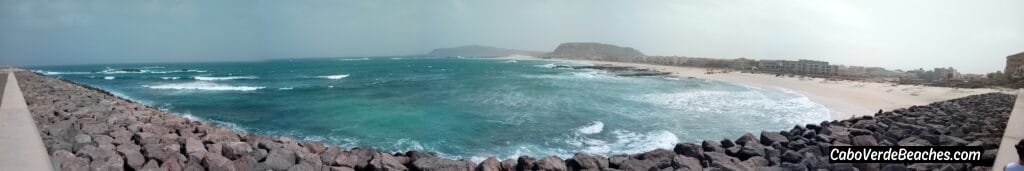 Golden sand and clear blue waters at the secluded Praia de Marmeleiro on Boa Vista, Cape Verde, surrounded by rugged coastal cliffs.